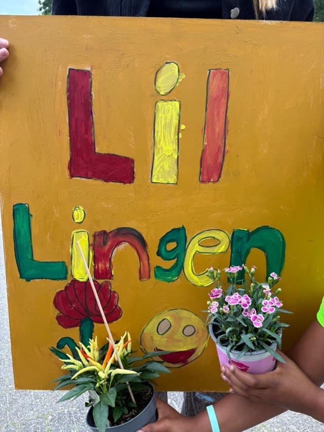 Kinder präsentieren ein selbst gestaltetes Schild der Kinderstadt Lil Lingen